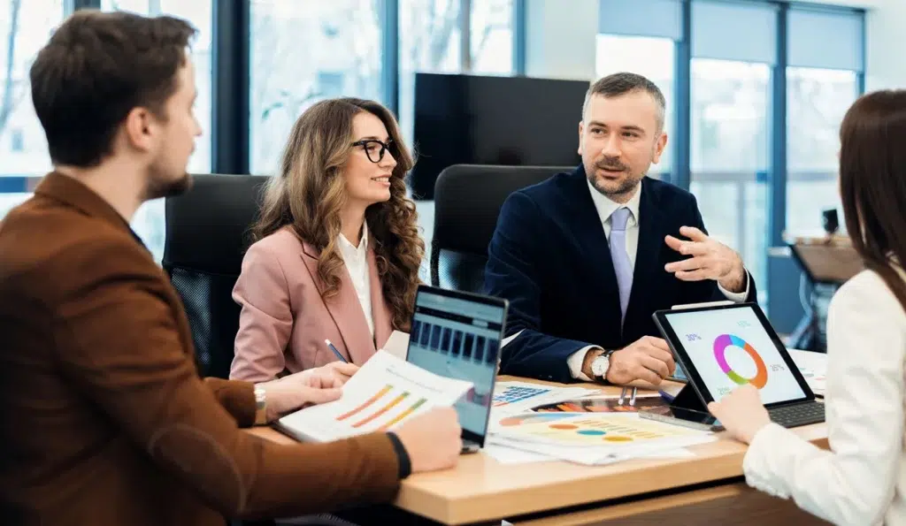 Profesionales en una reunión utilizando gráficos y dispositivos, mejorando la eficiencia con herramientas de IA generativa